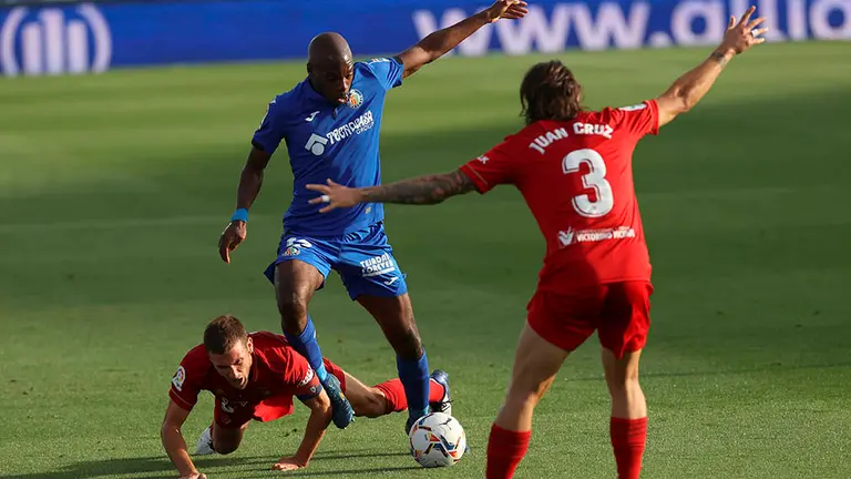 El defensa camerunés del Getafe, Allan Romeo Nyon (c), se lleva el balón ante el jugador de Osasuna, David García (i), durante el encuentro correspondiente a la segunda jornada de primera división disputado esta tarde en el Coliseum Alfonso Pérez, en la localidad madrileña. EFE/JuanJo Martín.