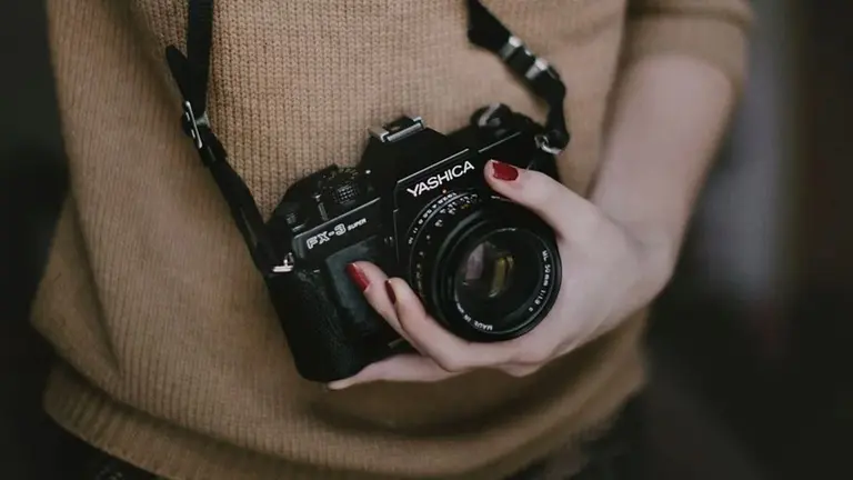 Una mujer sostiene una cámara de fotos. ARCHIVO