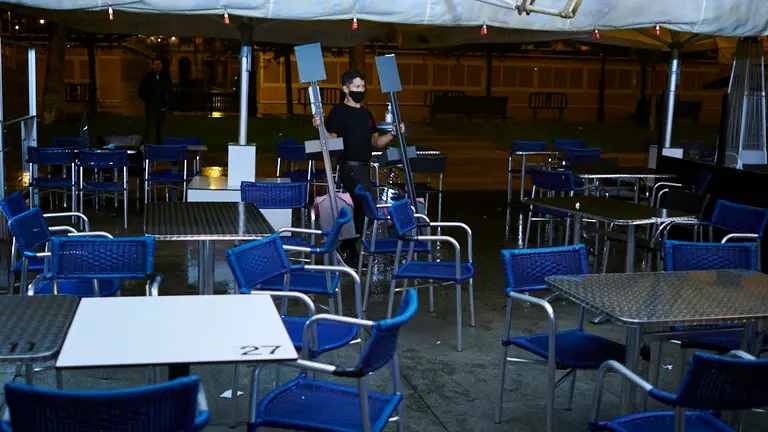 El responsable de un bar, recoge la terraza, durante el horario establecido por la crisis del coronavirus. PABLO LASAOSA