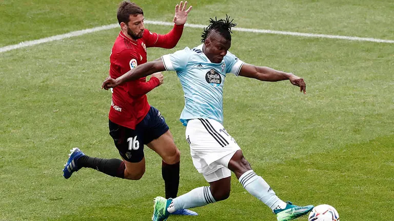 El delantero argentino del Osasuna Jonathan Calleri (i) lucha por el balón con el defensa ghanés Joseph Aidoo, del Celta de Vigo, durante el partido de LaLiga Santander de fútbol disputado este domingo en el Estadio de El Sadar, en Pamplona. EFE/Jesús Diges