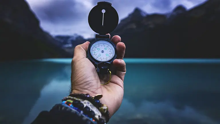 Un hombre sostiene una brújula en una montaña.