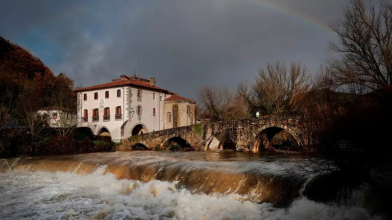 Un hombre corre al aire libre cruzando el Puente Viejo de Arre sobre el río Ultzama en Navarra que muestra un registro muy caudaloso pero estable o con tendencia descendente sin que se hayan producido desbordamientos significativos como consecuencia de las lluvias registradas en las últimas horas y del deshielo de la nieve acumulada en los montes, este sábado en Pamplona. EFE/Villar López