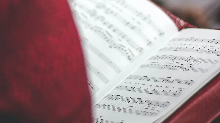 Un hombre sujeta una partitura mientras canta en un coro. ARCHIVO