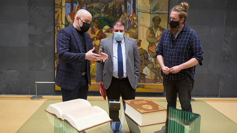 Aritz Otazu, de la editorial Mintzoa; el presidente del Parlamento, Unai Hualde; y Maiorga Ramírez, de EH Bildu; con un volumen de 'La Gran Historia de Navarra' de 1632. PARLAMENTO DE NAVARRA