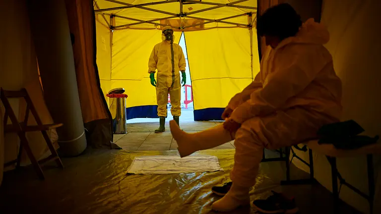 Una mujer se viste con un EPI para hacerle el relevo a un compañero, desifectando ambulancias y camillas en urgencias del Complejo Hospitalario de Navarra el 27 de marzo. PABLO LASAOSA