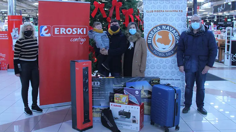 La familia del agraciado posa con el lote de regalos sorteado por el Ribera Navarra FS. Cedida.