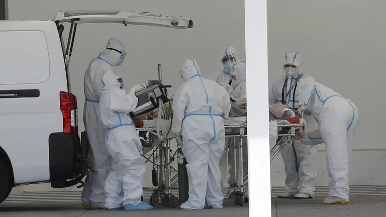 Varios sanitarios alrededor de una persona fallecida por coronavirus. EFE/Rodrigo Sura