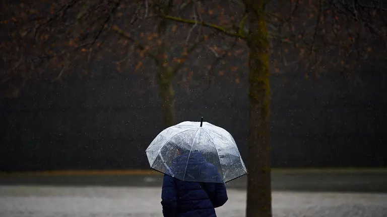 Una mujer con paraguas camina bajo la lluvia por las calles de Pampolona durante la tercera ola del coronavirus en la Comunidad Foral. MIGUEL OSÉS