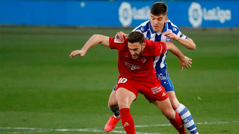 El defensa del Alavés Martín Aguirregabiria (detrás) pelea un balón con el centrocampista de Osasuna Roberto Torres durante el partido de LaLiga que se disputa este sábado en el estadio de Mendizorroza. EFE /Adrián Ruiz Hierro