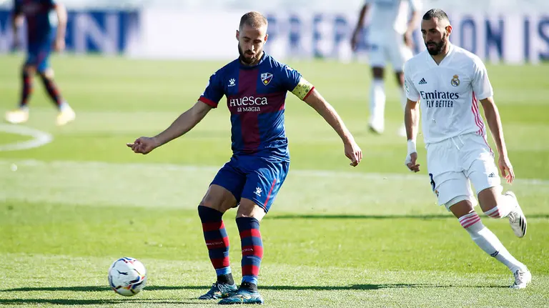 Jorge Pulido controla el balón ante Benzemá en el partido Huesca - Real Madrid. Europa press.