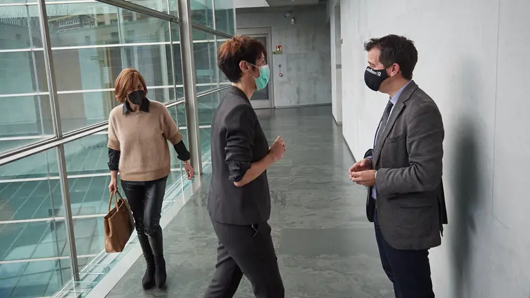 La consejera de Economia y Hacienda Elma Saiz habla con el consejero de desarrollo económico Mikel Irujo, mientras pasa la portavoz de Geroa Bai, Uxue Barkos. MIGUEL OSÉS