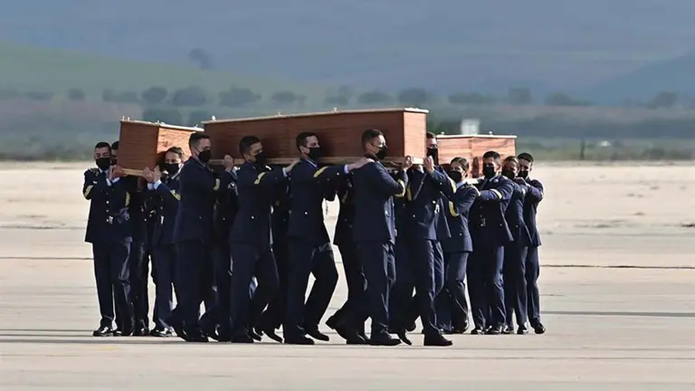 Varios militares llevan a hombros los féretros con los restos mortales de los periodistas David Beriáin y Roberto Fraile y del conservacionista irlandés Rory Young, asesinados este lunes durante la grabación de un documental en Burkina Faso, a su llegada este viernes a la base aérea de Torrejón de Ardoz. EFE/Fernando Villar