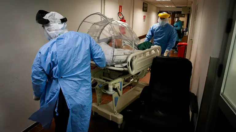 Dos sanitarios trasladan a una persona con Covid en una camilla. EFE/Raúl Martínez/Archivo