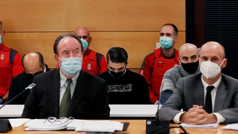 GRAFCAV5457. PAMPLONA, 24/05/2021.- La Audiencia Provincial de Navarra acoge desde este lunes el juicio con jurado por un triple crimen perpetrado en Cáseda en septiembre de 2018, tras el enfrentamiento entre dos familias. En sus conclusiones provisionales, el fiscal solicita 60 años de prisión —20 por cada uno de los tres delitos de asesinato— para los tres acusados —padre y dos hijos— de la muerte de Fermín J.E., de 50 años, y de dos de sus hijos, José Antonio y Cristian, de 20 y 17 años, quienes fallecieron a consecuencia de los disparos de escopeta recibidos. En la imagen, en primer termino dos de los abogados de los acusados y detrás los tres procesados. EFE/Jesús Diges POOL

