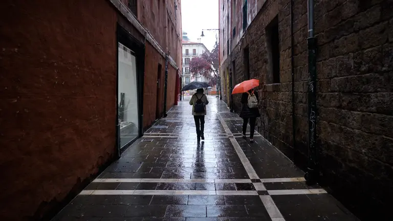 Una mujer camina por las calles de Pamplona con un paraguas durante una tormenta de la primavera de 2021. MIGUEL OSÉS
