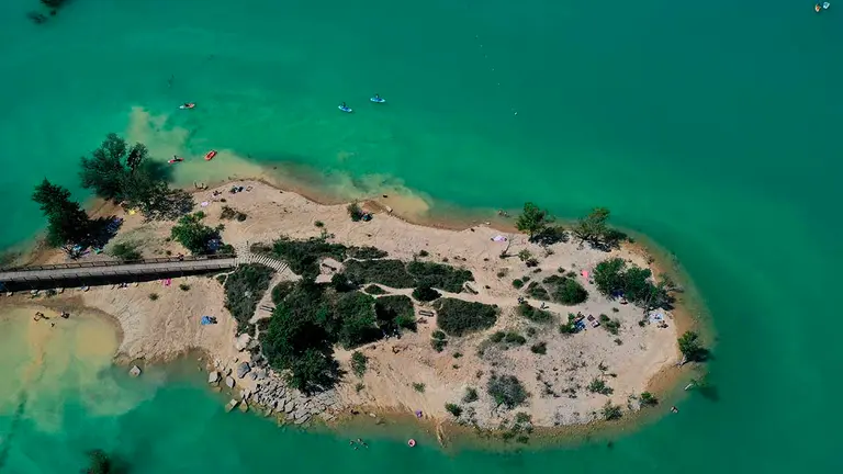 GRAFCAV5994. ALLOZ, 13/06/2021.-  Varias canoas navegan en las aguas del pantano de Alloz mientras algunos toman el sol en una peque&ntilde;a isla del pantano, en una jornada donde la Agencia Estatal de Meteorolog&iacute;a anuncia para este domingo viento flojo variable con predominio del sur y sureste durante las horas centrales, y temperaturas en ascenso, m&aacute;s acusado el de las m&aacute;ximas que hoy han alcanzado los 34 grados.   EFE/ Jes&uacute;s Diges
