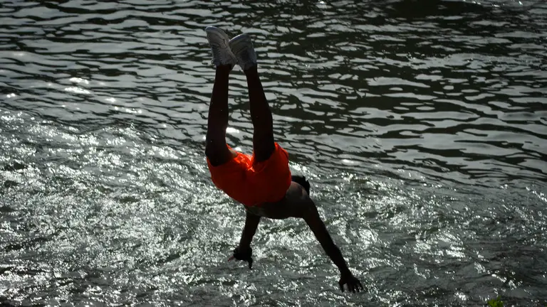 Varias personas aprovechan las altas temperaturas para bañarse en el rio junto al Club Natacion en Pamplona. MEGAN WALLS