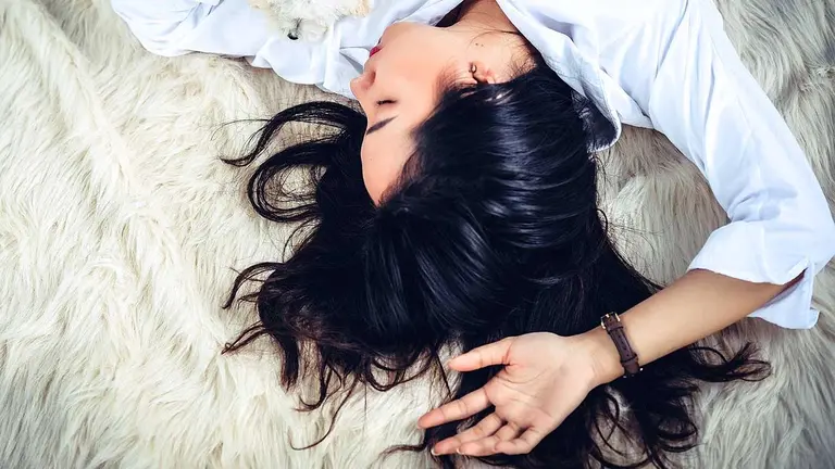 Una mujer descansa dormida en una cama. ARCHIVO