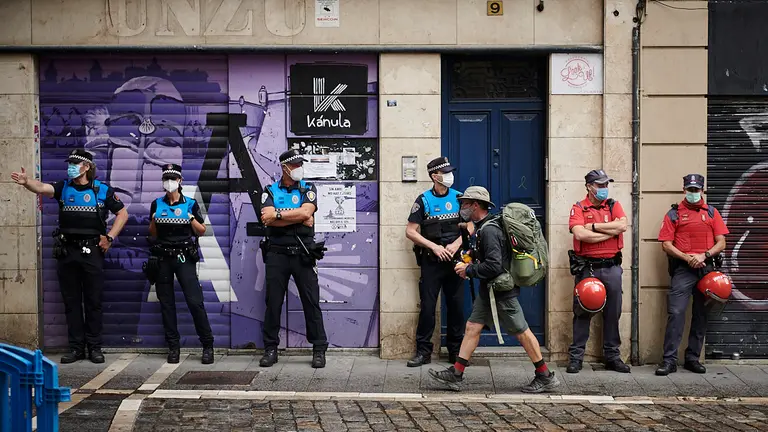 Un peregrino pasa delante de agentes de Policía en las no fiestas de San Fermín de 2021. PABLO LASAOSA