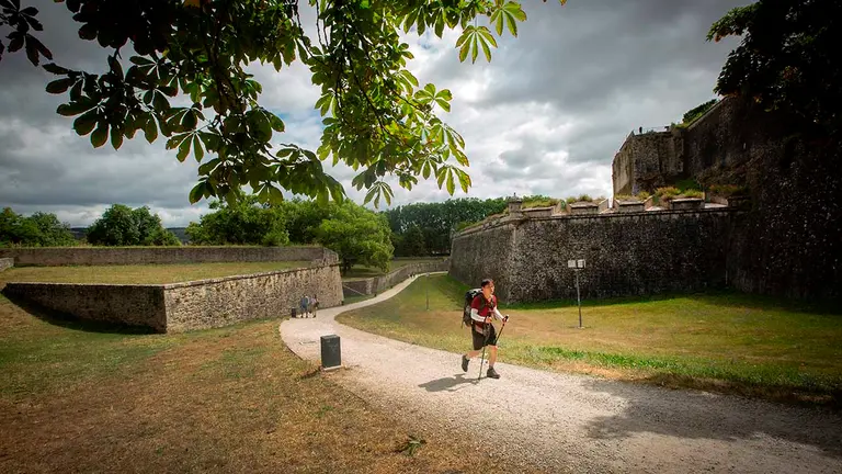 GRAF8911. PAMPLONA (NAVARRA), 03/08/2021.- Un peregrino del Camino de Santiago hace su entrada a Pamplona por las murallas. La localidad francesa de Saint-Jean-Pied-de-Port y la española de Pamplona delimitan en sus extremos un corredor verde de 80 kilómetros, denominado "Kintoan Barna", que tiene el monte de Quinto Real, frontera natural entre ambos países, como su núcleo vertebrador. EFE/Villar López
