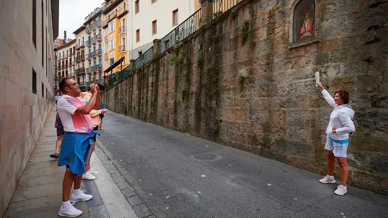 GRAF8915. PAMPLONA (NAVARRA), 03/08/2021.- Un grupo de turistas se fotografían en la cuesta de Santo Domingo ante la horancina de San Fermin en pleno recorrido del encierro de los Sanfermines. La localidad francesa de Saint-Jean-Pied-de-Port y la española de Pamplona delimitan en sus extremos un corredor verde de 80 kilómetros, denominado "Kintoan Barna", que tiene el monte de Quinto Real, frontera natural entre ambos países, como su núcleo vertebrador. EFE/Iñaki Porto
