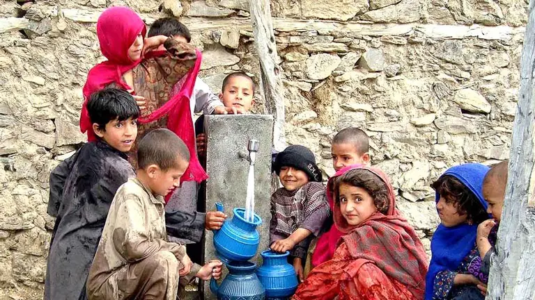 Unos niños y niñas recogen agua de un poblado de Afganistán. ARCHIVO