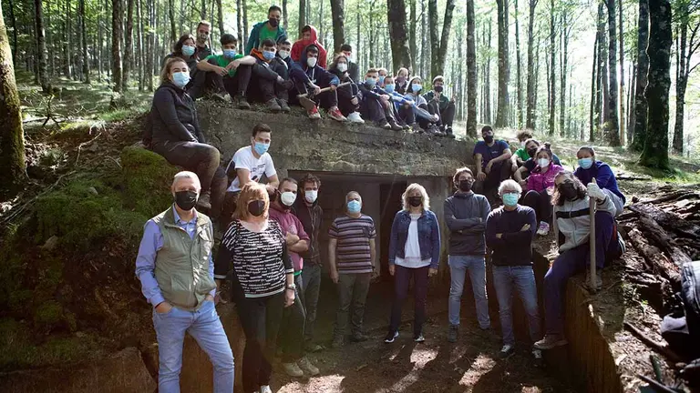 Los y las representantes del Gobierno de Navarra Martin Zabalza, la consejera Ana Ollo, Carlos Amatriain y José Mª Gastón, acompañados por Maite Errea, concejante de Eugi , y por responsables y participantes en el campo, en la entrada de uno de los búnkeres. GOBIERNO DE NAVARRA