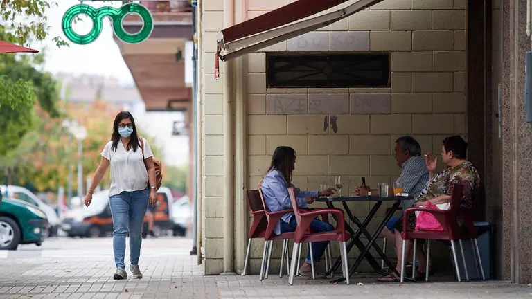 Una mujer camina por delante de una terraza en los ultimos dia del verano de 2021 durante la crisis del coronavirus en la Comunidad Foral. MIGUEL OSÉS