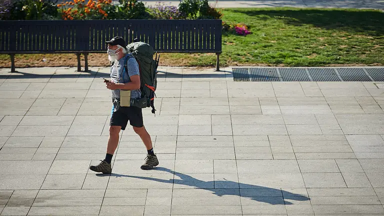 Un peregrino con mascarilla camina por la Plaza del Castillo de Pamplona. PABLO LASAOSA