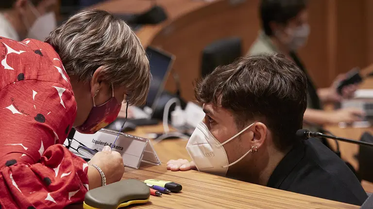 El parlamentario de Geroa Bai Pablo Azcona habla con la parlamentaria de I-E Marisa de Simón en el pleno del Parlamento de Navarra. EUROPA PRESS