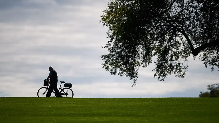 Un hombre camina con su bicicleta por la vuelta del castillo durante los últimos dias del verano de 2021. MIGUEL OSÉS