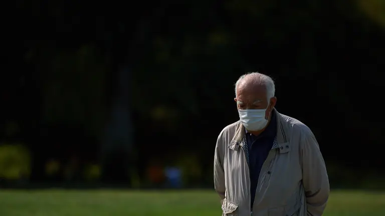 Un hombre con mascarilla camina por la vuelta del castillo de Pamplona durante los últimos dias del verano de 2021. MIGUEL OSÉS