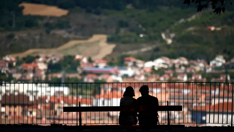 Una pereja sentada en un banco en la Taconera de Pamplona durante los últimos dias del verano de 2021. MIGUEL OSÉS