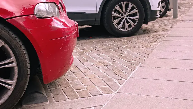 Imagen de varios coches estacionados con topes para que no accedan a la acera. PSN