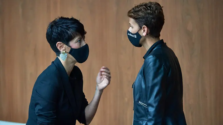 La presidenta del gobierno de Navarra, María Chivite (d), habla con la consejera de Economía y Hacienda, Elma Saiz (i), durante el pleno en el Parlamento. NIGUEL OSÉS