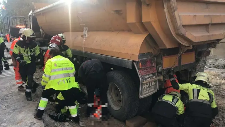 Los bomberos desatrapan de entre los ejes de un camión a un trabajador en la calle General Chinchilla de Pamplona. BOMBEROS DE NAVARRA