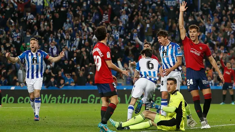 El centrocampista de Osasuna, Lucas Torró (d), reclama fuera de juego ante la celebración del defensa de la Real Sociedad, Aritz Elustondo (3i), en el primer gol del equipo donostiarra durante el encuentro correspondiente a la jornada 26 de primera división disputado hoy domingo en el Reale Arena de San Sebastián. EFE / Javier Etxezarreta.