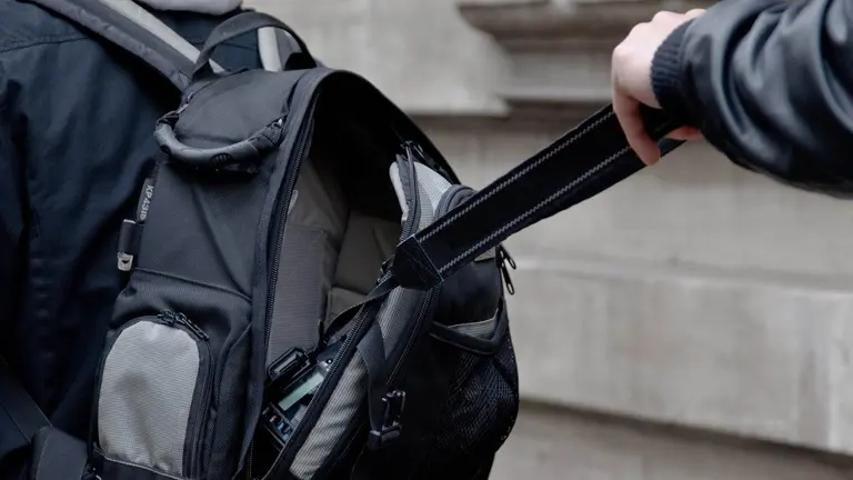 Un ladrón hurtando una cámara de fotos de una mochila ARCHIVO