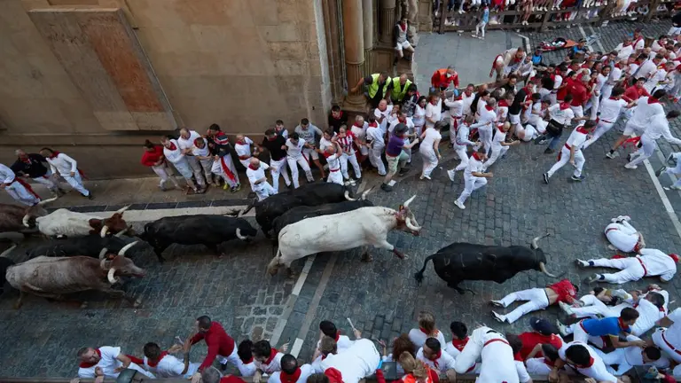 Varios mozos esquivan a los toros de la ganadería gaditana de Fuente Ymbro en el tramo desde el final de la cuesta de Santo Domingo a la curva de Mercaderes durante el segundo encierro de los Sanfermines 2022. EFE/J.P. Urdiroz