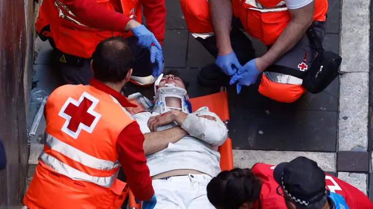 Sanitarios de Cruz Roja trasladan a uno de los mozos que ha resultado herido tras corren ante los toros de la ganadería de José Escolar durante el tercer del encierro de San Fermín, este sábado. EFE/ Rodrigo Jimenez