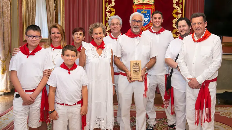 El periodista jubilado Javier Solano sostiene el regalo del Ayuntamiento de Pamplona rodeado por su familia. Cedida.
