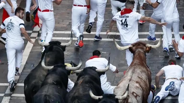 Los mozos corren por la calle de Mercaderes durante el séptimo encierro de los Sanfermines ante los toros de la ganadería de Victoriano del Río Cortés. este miércoles en Pamplona. EFE Jesus Diges