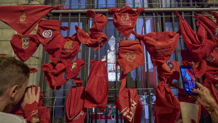 Pamploneses y visitantes dejan velas y pañuelos a las puertas de la iglesia de San Lorenzo, en cuyo interior se encuentra la capilla de San Fermín, tras el "Pobre de mí" de los Sanfermines 2022. IÑIGO ALZUGARAY