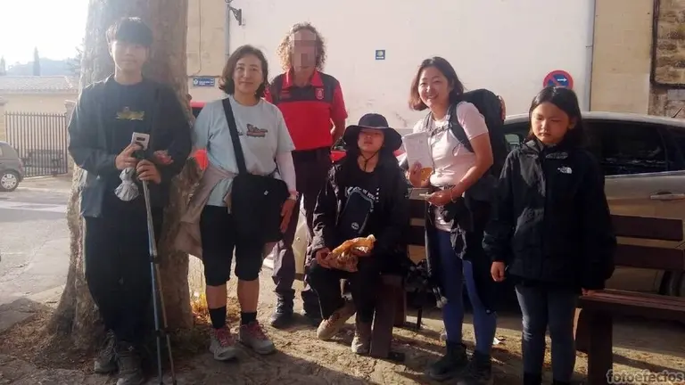 Madre e hija, en el centro de la imagen, una vez producido el reencuentro, posan con el agente de la patrulla ciudadana que llevó la gestión. CEDIDA