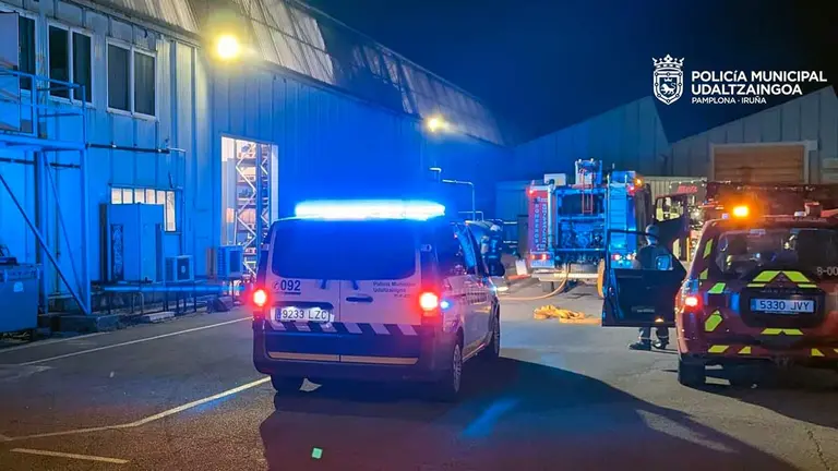 Una patrulla de la Policía Municipal de Pamplona junto a un todoterreno de los bomberos ante la sede de la empresa que ha sufrido el incendio. POLICÏA MUNICIPAL DE PAMPLONA