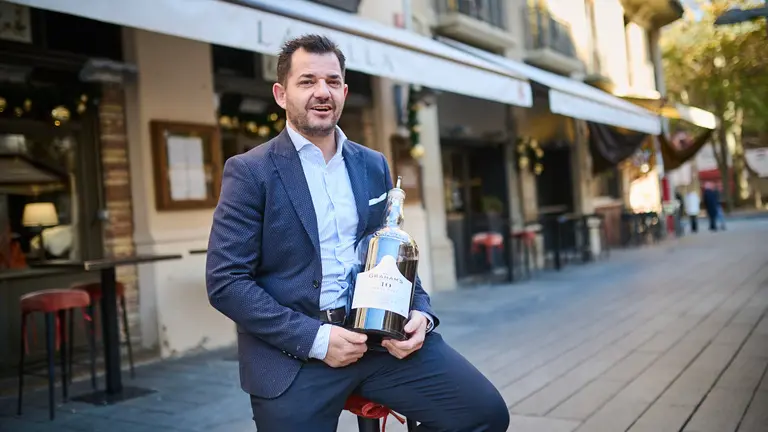 Fermín de Prados sostiene la botella de Grahams's delante del restaurante La Olla. Pablo Lasaosa.