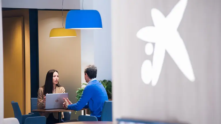 Una trabajadora de Caixabank asesora a un cliente en una de las oficinas de la compañía. CAIXABANK