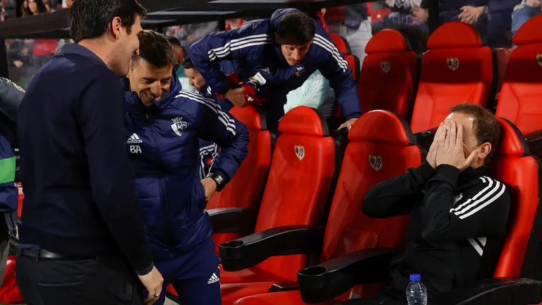 Jagoba Arrasate (d), técnico del CA Osasuna, ríe tapándose la cara momentos antes de comenzar el partido de la Jornada 29 de LaLiga Santander que ambos equipos disputan en el Campo de Fútbol de Vallecas, este viernes. EFE/ Juanjo Martin