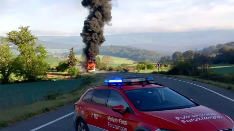 Imagen del autobús en llamas ante un coche patrulla de la Policía Foral. POLICÍA FORAL
