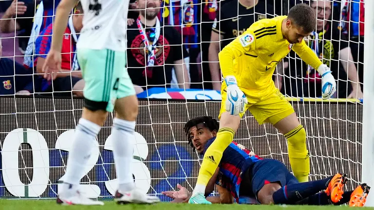 El defensa francés del FC Barcelona, Jules Koundé, en el suelo ante el guardameta de Osasuna, Aitor Fernández, durante el partido correspondiente a la jornada 33 de LaLiga Santander que disputan FC Barcelona y CA Osasuna este martes en el Spotify Camp Nou de la Ciudad Condal. EFE/ Enric Fontcuberta.